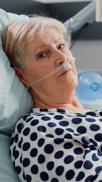 Portrait de vieux patient couché au lit avec un tube d'oxygène nasal - Photo, image