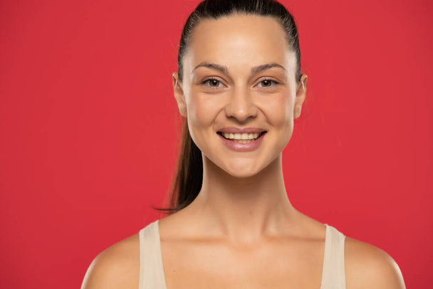 Muotokuva kaunis hymyilevä nainen sidottu hiukset punaisella pohjalla - Valokuva, kuva