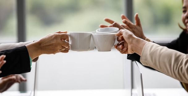 Крупним планом знімок чашок кави в руках невпізнаваної групи ділових партнерів у формальному діловому одязі, що підбадьорює тости разом після завершення планування роботи
. - Фото, зображення