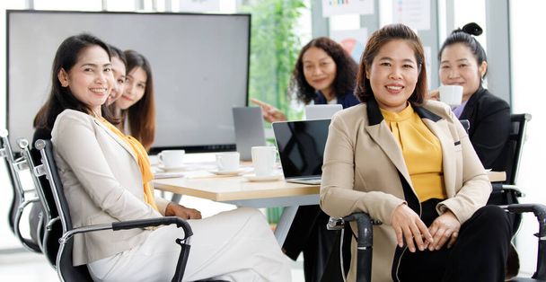 Group of Asian middle aged happy successful relaxing female businesswoman officer worker staffs in formal suit sitting on chairs smiling take coffee break together in meeting room. - Photo, Image