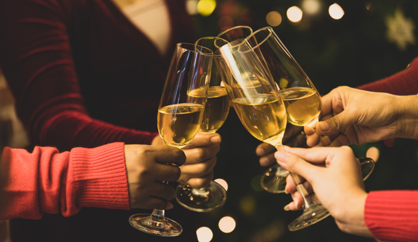 Beverage glasses clinking moment by cheerful woman friends on sweater as enjoy celebrating happy relationship at delightful event of Chirstmas night party. Add some noise to fit vintage-style image. - Foto, Imagem