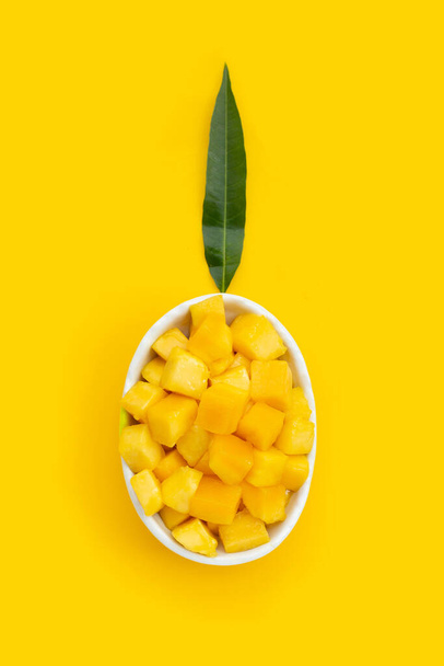 トロピカルフルーツ、マンゴーキューブ黄色の背景に白いボウルにスライス. - 写真・画像