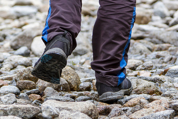 Un hombre en las montañas caminando sobre piedras - Foto, Imagen