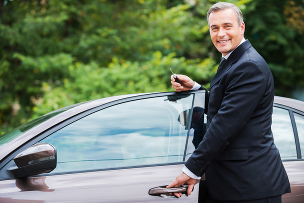 Зрілий чоловік в формальному одязі стоїть біля своєї нової машини
 - Фото, зображення