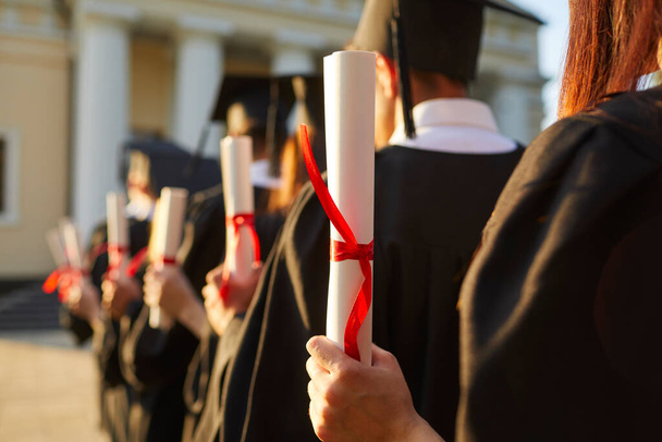 Graduate.Selective focus on degree diploma certificate in hand of student standing in row - Foto, Imagen