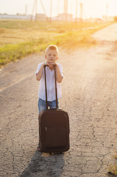 the boy holds a suitcase in a summer sunny day - Φωτογραφία, εικόνα