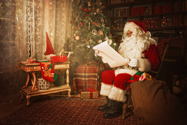 Santa Claus reading from a Christmas wish list - Fotoğraf, Görsel