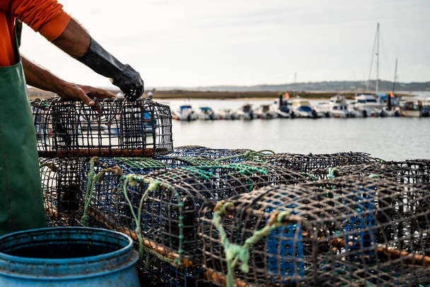 Рыбак кладет крабов в ловушки для осьминогов в Алворе, Алгарве, Португалия - Фото, изображение