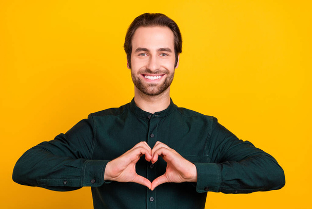 Photo of pretty charming young man wear smart casual outfit showing arms heart isolated yellow color background - Fotoğraf, Görsel