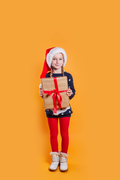 Happy little smiling girl in Santa hat with big christmas gift box - Photo, image