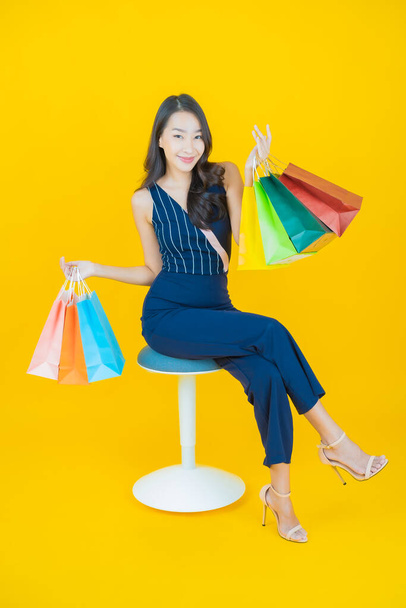 Porträt schöne junge asiatische Frau lächeln mit Einkaufstasche auf farbigem Hintergrund - Foto, Bild