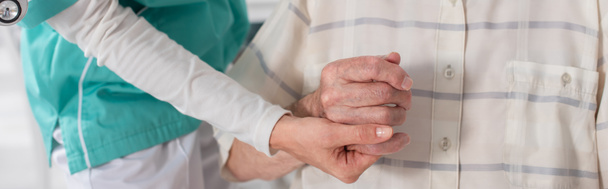 Huzurevinde yaşlı bir hastanın elini tutan genç hemşire görüntüsü.  - Fotoğraf, Görsel