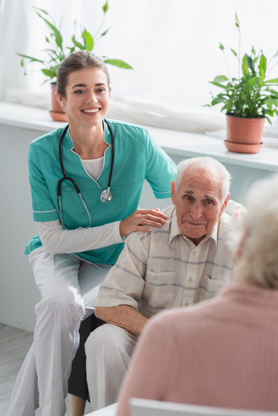 Glückliche Krankenschwester umarmt Seniorin im Pflegeheim  - Foto, Bild
