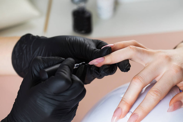 Manicure process in a beauty salon. The manicurist paints the nail with varnish. - Fotó, kép