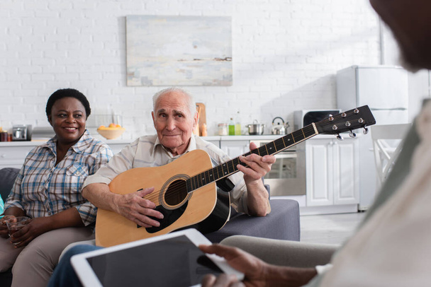 Multiethnic senior people with acoustic guitar and digital tablet in nursing home  - Foto, afbeelding