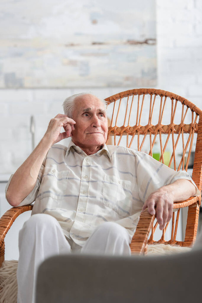 Grey haired man looking away in rocking chair in nursing home - Fotoğraf, Görsel
