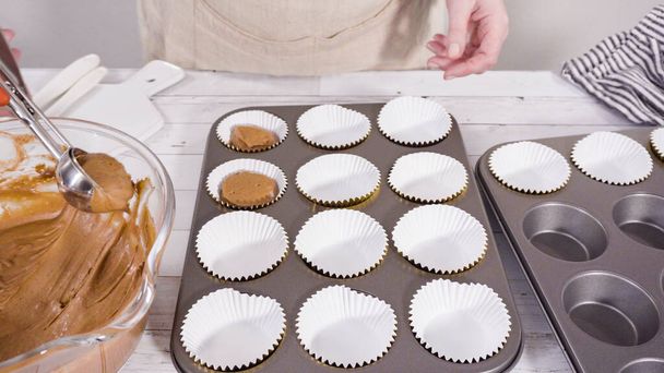 Scooping dough into the foil cupcake liners to bake chocolate raspberry cupcakes. - Фото, изображение
