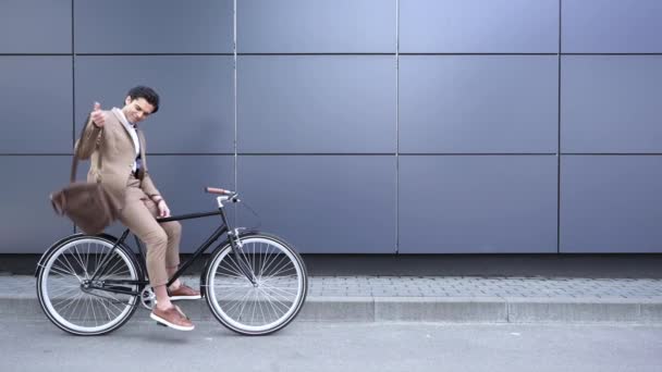 elégedett üzletember öltönyben lógó bőr aktatáska és kerékpározás - Felvétel, videó