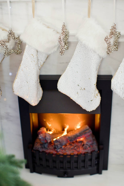 Calcetines blancos de Navidad y estrellas de plata con campanas colgando de la chimenea. Regalos de Navidad en calcetines - Foto, imagen