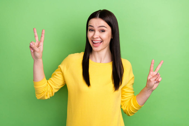 Photo portrait of woman showing v-sign gesture both hands laughing isolated on vibrant green color background - Zdjęcie, obraz