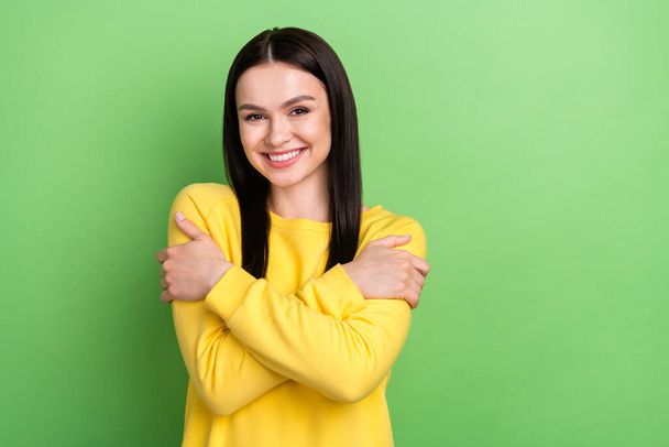 Portrait of attractive glad cheerful girl hugging herself copy space isolated over green color background - Foto, Imagem