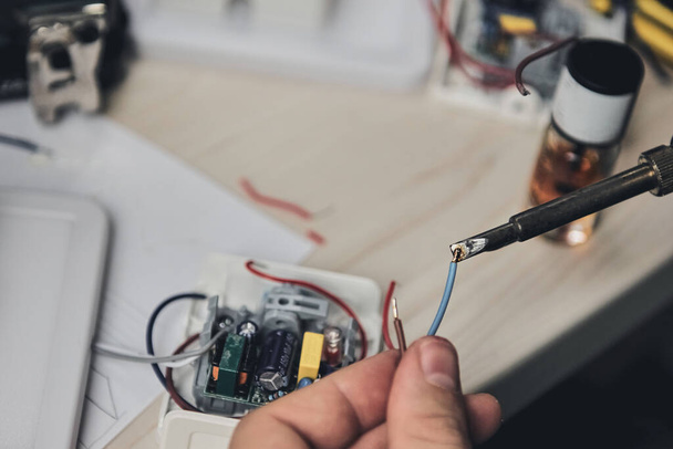 Reparatie van elektronische apparatuur, tin soldeer onderdelen. Handen van een man met een schroevendraaier. Computerprintplaat. - Foto, afbeelding