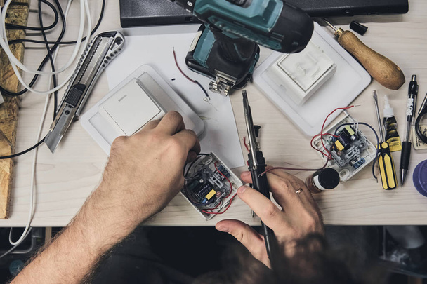 Reparatie van elektronische apparatuur, tin soldeer onderdelen. Handen van een man met een schroevendraaier. Computerprintplaat. - Foto, afbeelding