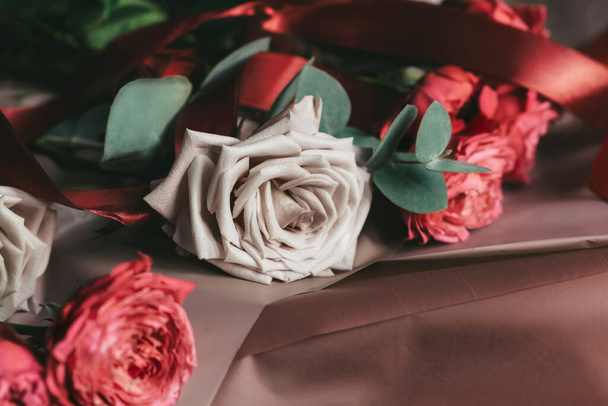 Pink roses on brown paper with ribbon. Preparing a bouquet for the holiday. Copy space - Fotó, kép