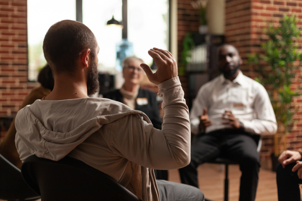 Hombre con adicción compartiendo problemas de salud mental con el grupo en una reunión aa - Foto, imagen