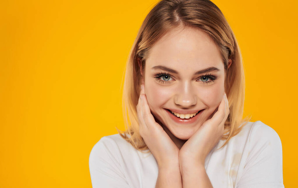 cheerful pretty blonde in a white t-shirt smile emotions yellow background - Photo, image