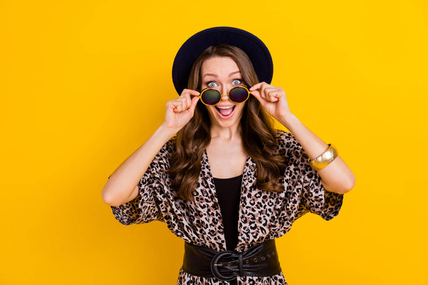 Photo of amazed charming cheerful young woman wear sunlgass sale news isolated on yellow color background - Fotografie, Obrázek