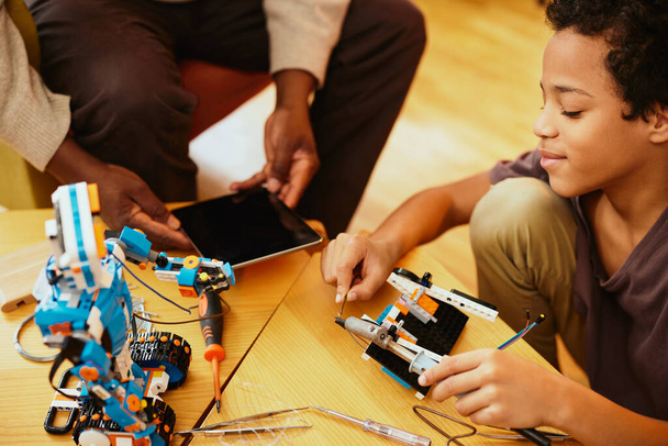 Un abuelo y un nieto haciendo un robot juntos en casa. Educación en robótica y electrónica. - Foto, imagen