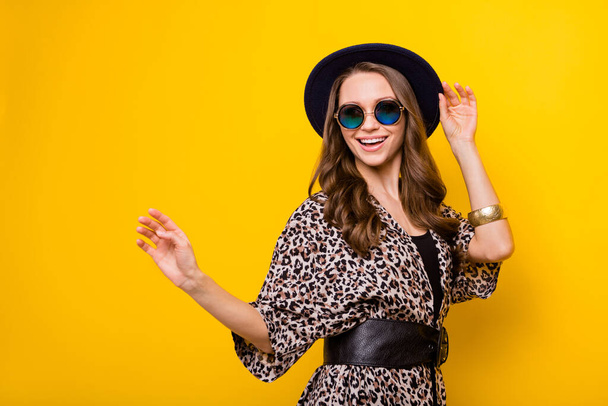 Фото веселой молодой женщины танцуют хорошее настроение носить очки прохладная шляпа изолированы на желтом фоне цвета - Фото, изображение