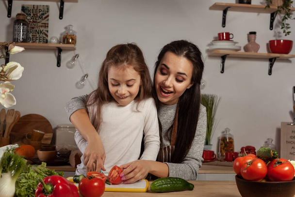 Anya és lánya van gyártás egy zöldség saláta és birtoklás móka a konyhában. - Fotó, kép