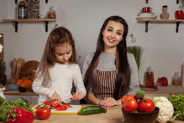 Мати і її дочка роблять овочевий салат і веселяться на кухні. - Фото, зображення