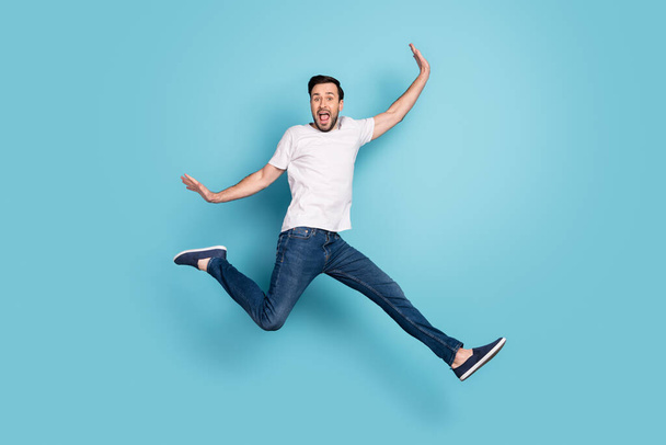 Full body photo of cheerful amazed young man jump up air raise hands isolated on pastel blue color background - Φωτογραφία, εικόνα