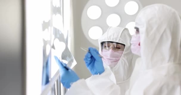 Dois médicos em trajes de proteção e máscaras examinar raios-X em laboratório filme 4k câmera lenta - Filmagem, Vídeo