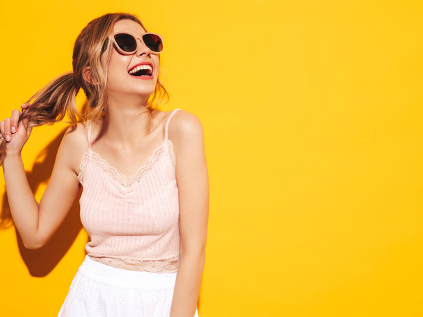 Young beautiful smiling female in trendy summer clothes. Sexy carefree woman posing near blue yellow in studio. Positive model having fun. Cheerful and happy. In sunglasses. Screaming and shouting - Photo, image
