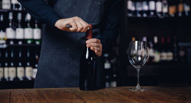 Banner Sommelier ανοίγει φελλό μπουκάλι κόκκινο κρασί με τιρμπουσόν - Φωτογραφία, εικόνα