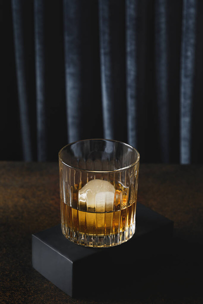 Cold whiskey served in rocks on dark blue curtain trendy background. Vertical format. Close up. - Photo, image