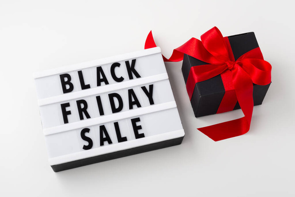 Black friday sale on light box with black gift box and red bow on white table - Fotoğraf, Görsel