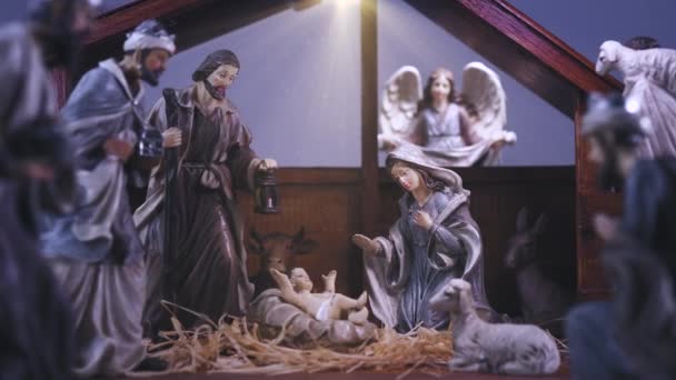 Jezus Christus Kerststal met beeldjes in stabiele en lichte deeltjes. Jezus Christus werd geboren in een kribbe met Maria en Jozef. Kerst scene. Dolly schot 4k - Video