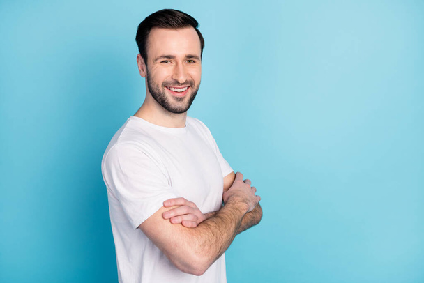 Profile photo of half turned satisfied glad man crossed arms beaming smile isolated on blue color background - Фото, зображення