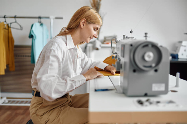Dressmaker sews cloth on sewing machine, workshop - Foto, immagini