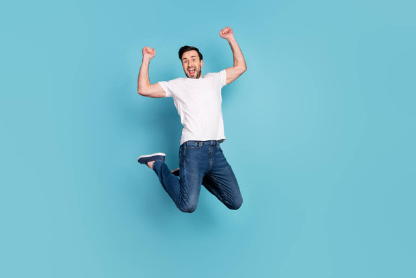 Full size portrait of astonished handsome guy fists up open mouth celebrate isolated on blue color background. - Photo, Image