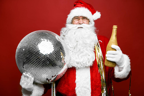 白人サンタクロースはシャンパンとディスコボールのボトルで祝う - 写真・画像