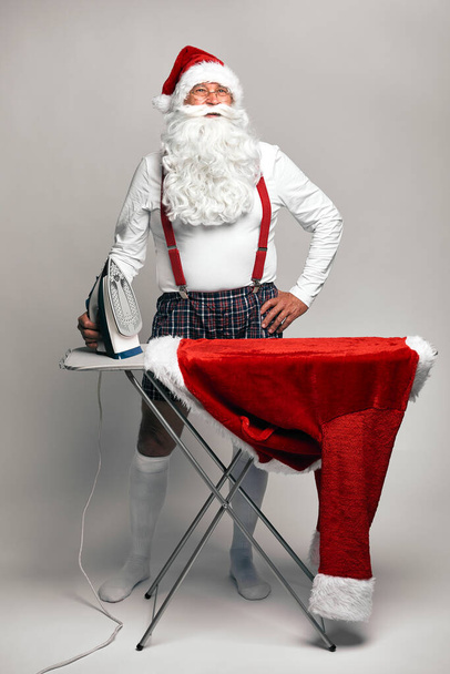 Caucasian Santa Claus ironing trousers for Christmas  - Foto, imagen
