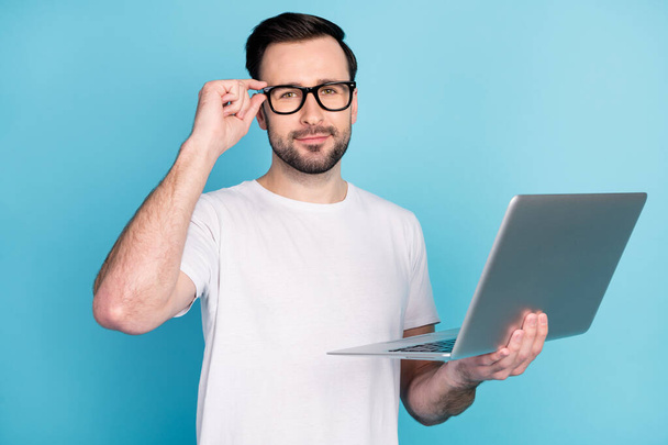 Porträt der zufriedenen Person Hand Touch Brille Look Kamera halten Laptop isoliert auf blauem Hintergrund. - Foto, Bild