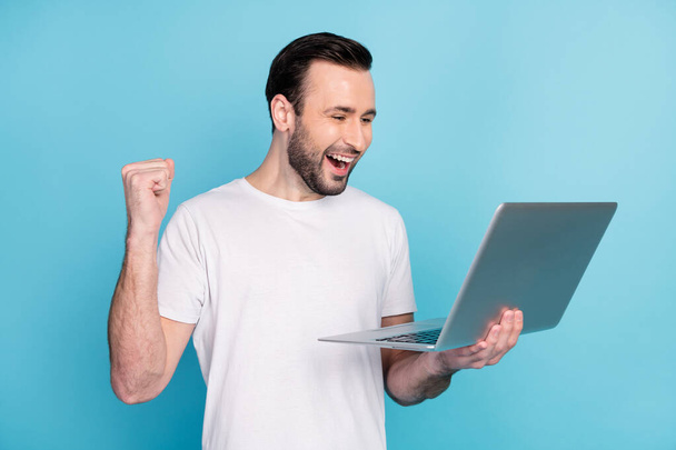 Photo of positive astonished man fist up open mouth celebrate look laptop isolated on blue color background. - Fotografie, Obrázek