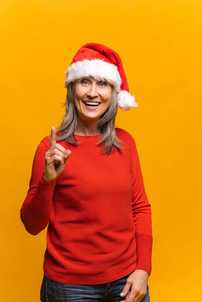 Pretty happy senior woman wearing santa hat - Foto, Imagen